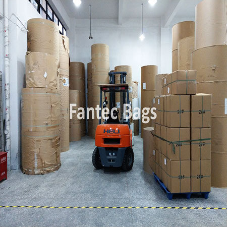 "Forklift moving rolls and boxed packaging materials prepared for shipment in a warehouse."