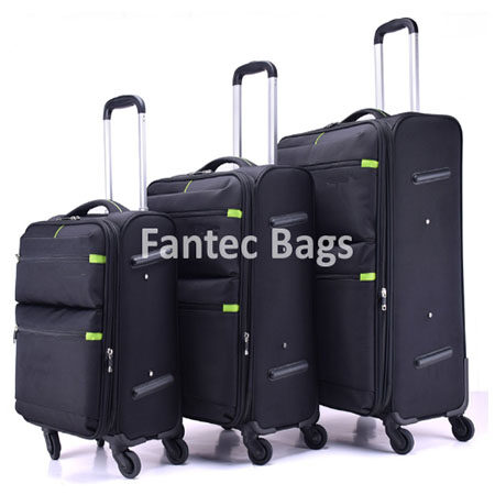 "Set of three black polyester suitcases with telescopic handles, zippered compartments, and green accent details."