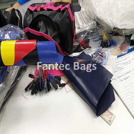 "Fabric pieces and zipper pulls organized for waterproof PVC bag assembly."
